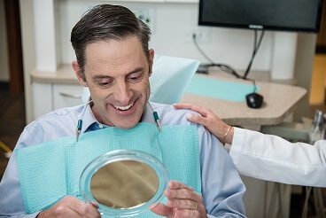 Patient looking in mirror asking are dental implants worth it